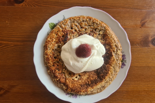 Na dřevěném stole je talíř s ovesnou plackou